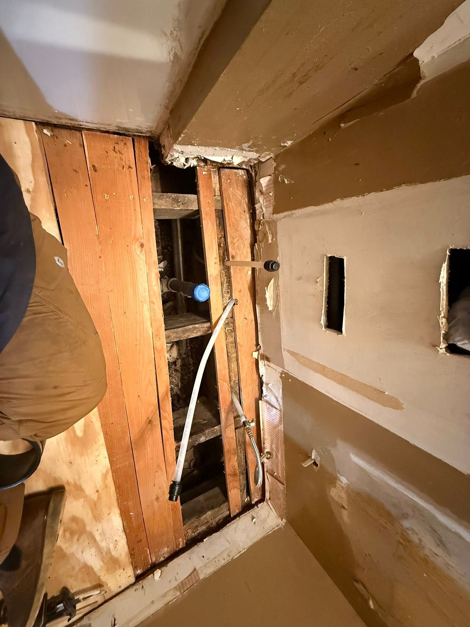 Plumbing in wall cavity; wood framing, white pipe, electrical outlets.