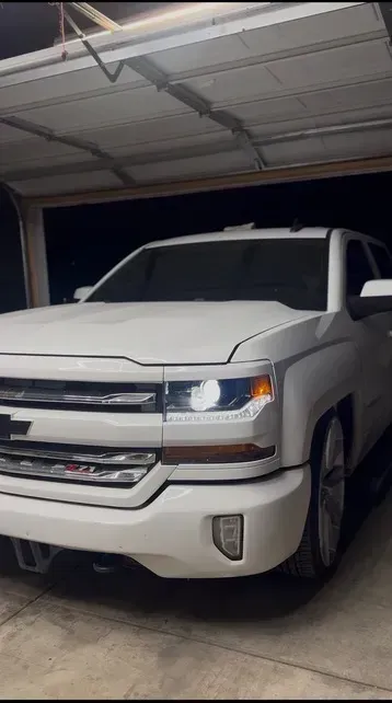 Black Corvette in a garage with hexagon-shaped lights. Garage has advertising posters hanging on the wall.