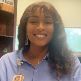 A woman in a blue shirt has a name tag on her chest