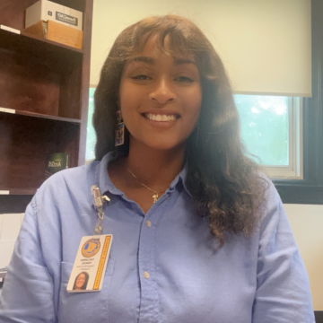 A woman in a blue shirt has a name tag on her chest