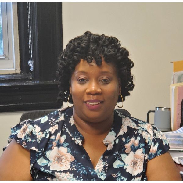A woman in a floral shirt sits at a desk