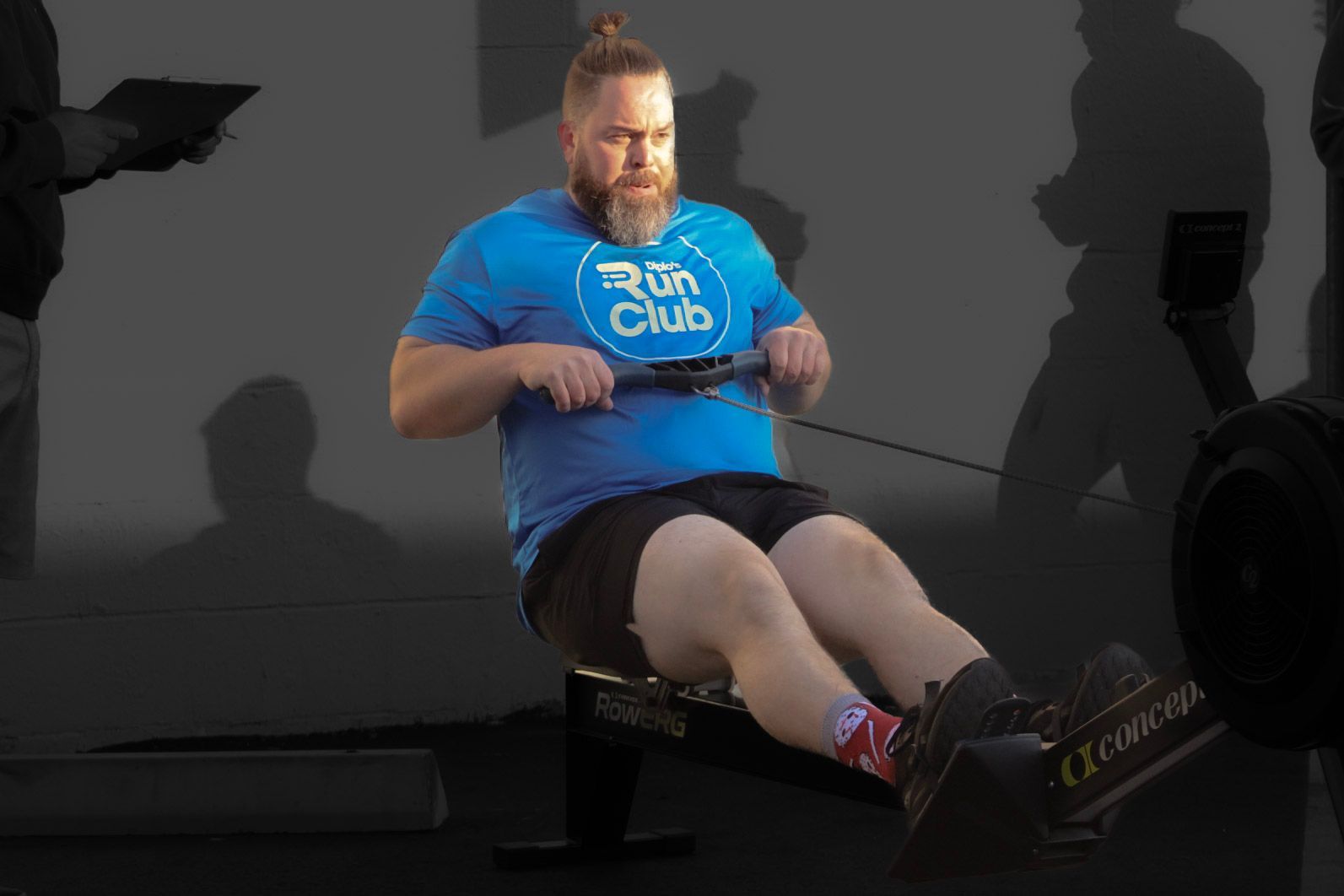 Woman and man doing box jumps in a gym, woman in squat position, man mid-air.