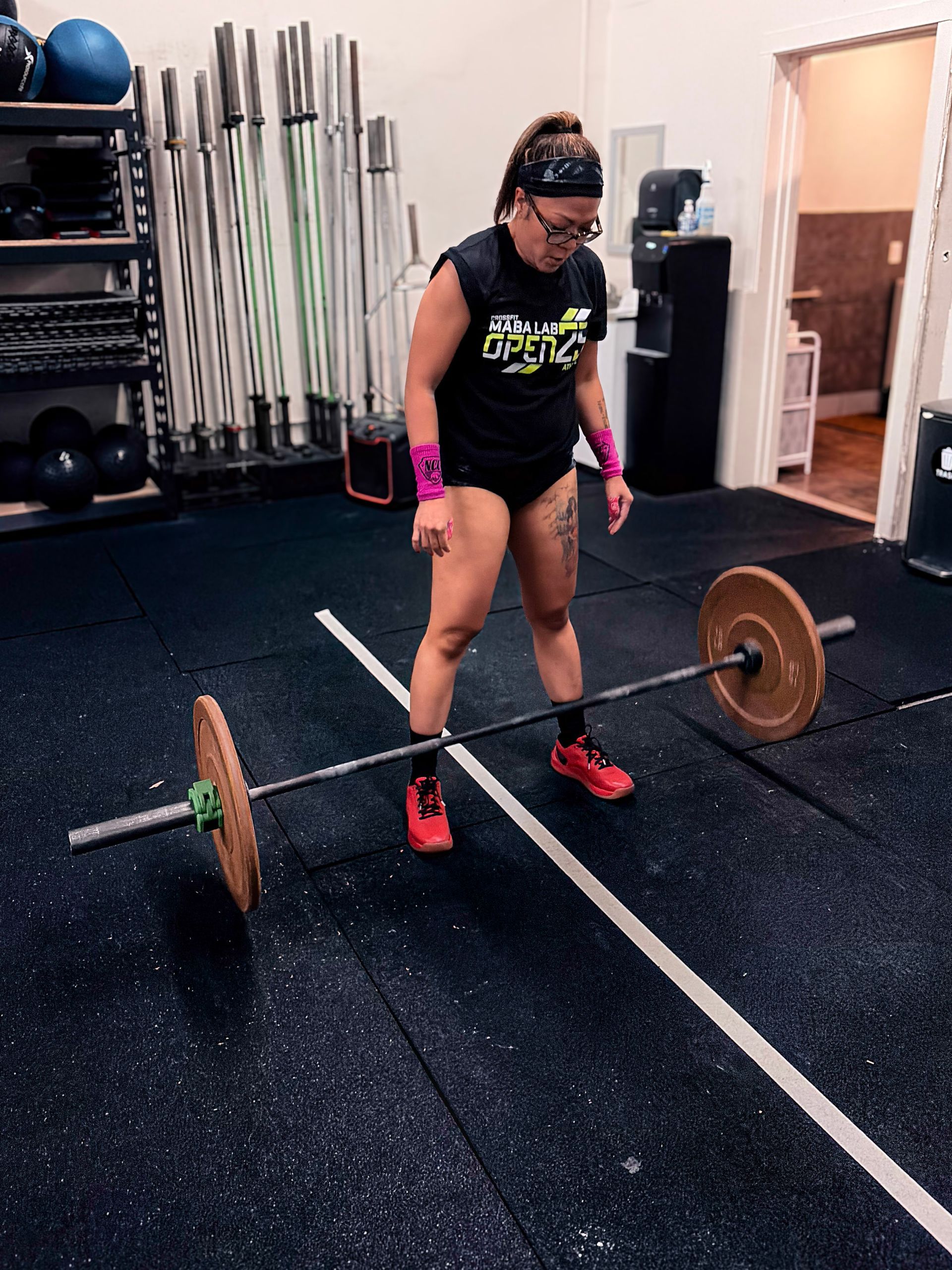 Four people in a gym jumping with arms raised, exercise in progress.