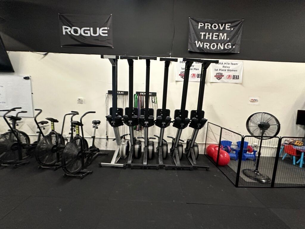 Gym interior with air bikes and a small enclosed play area.