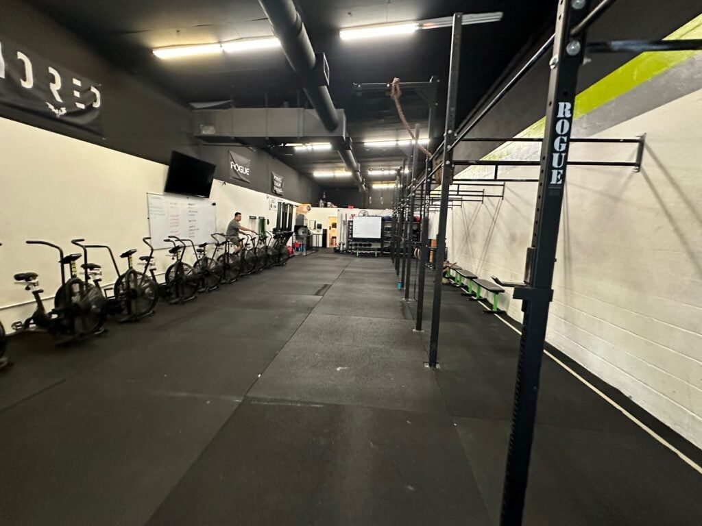 Gym interior with rows of stationary bikes, pull-up bars, and exercise equipment.