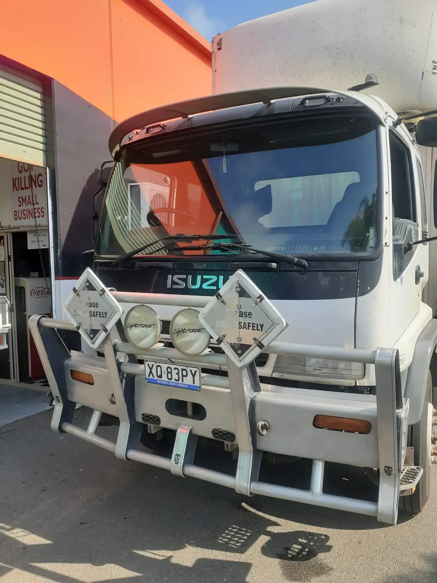 White Isuzu truck with a bull bar, spotlights, and visor parked outside a building. — Hervey Bay Mobile Windscreens in Pialba, QLD
