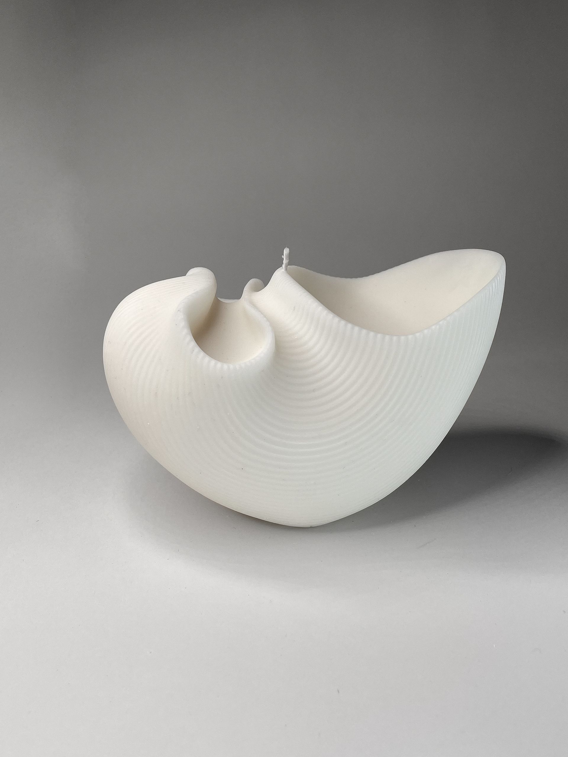 Een wit beeld staat op een wit oppervlak.