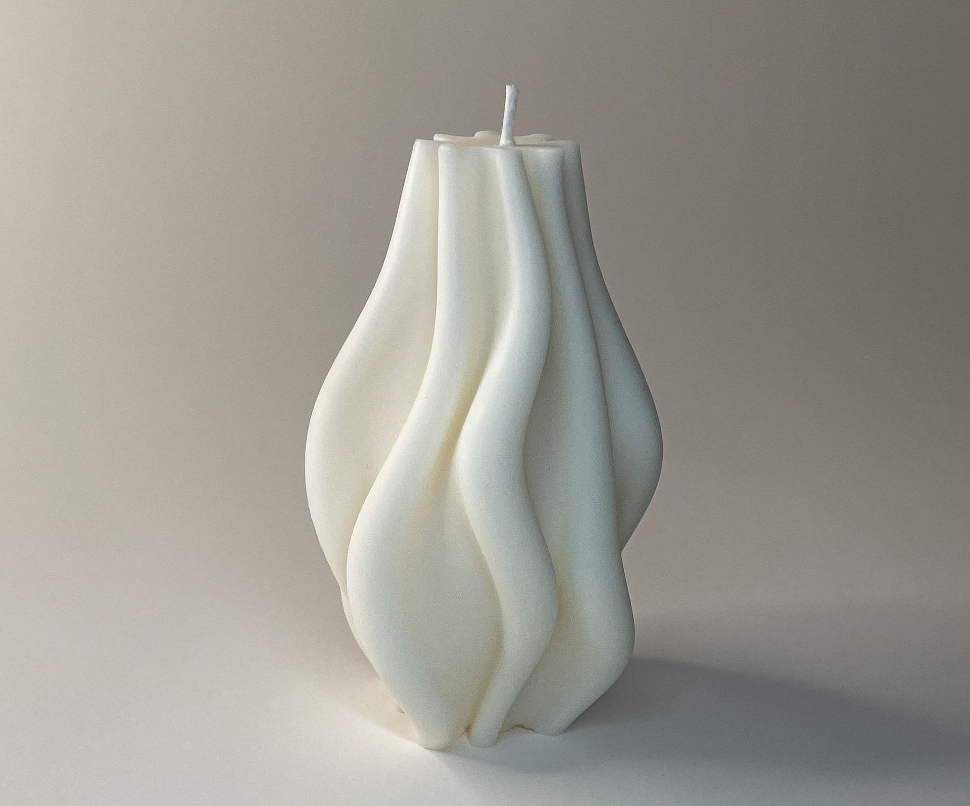 Een witte kaars staat op een wit oppervlak