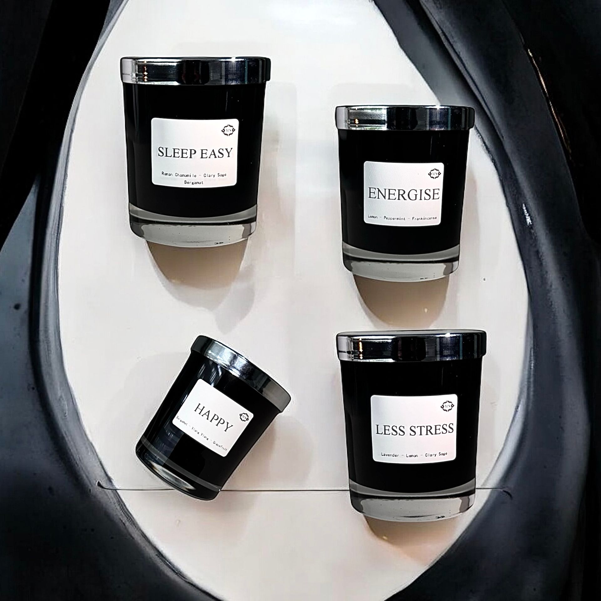 Vier zwarte kaarsen staan op een wit oppervlak en op een ervan staat slaap lekker