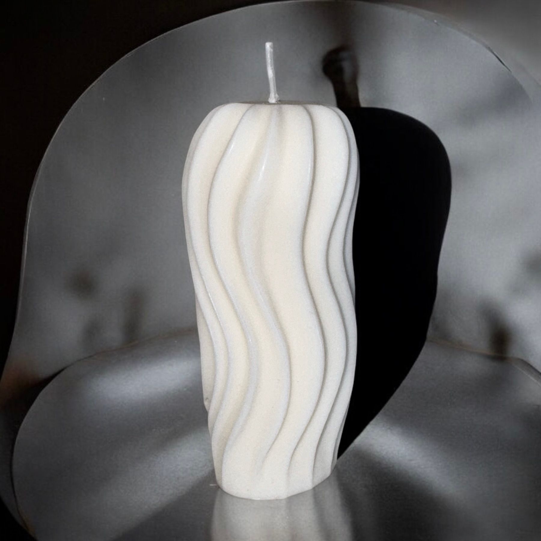 Een witte kaars staat op een metalen oppervlak.