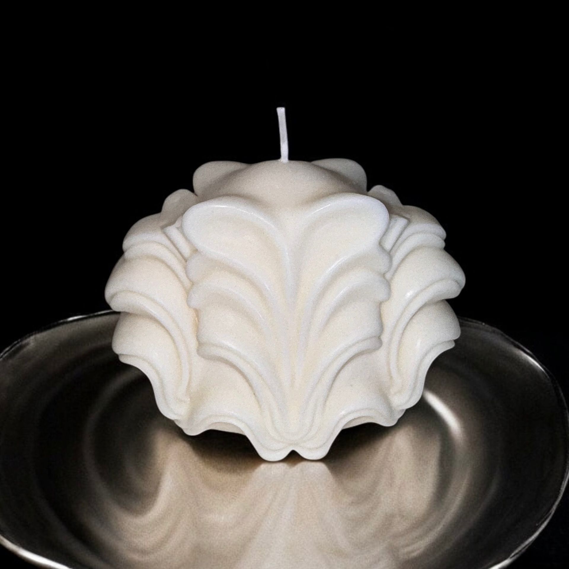 Een witte kaars staat op een zilveren bord