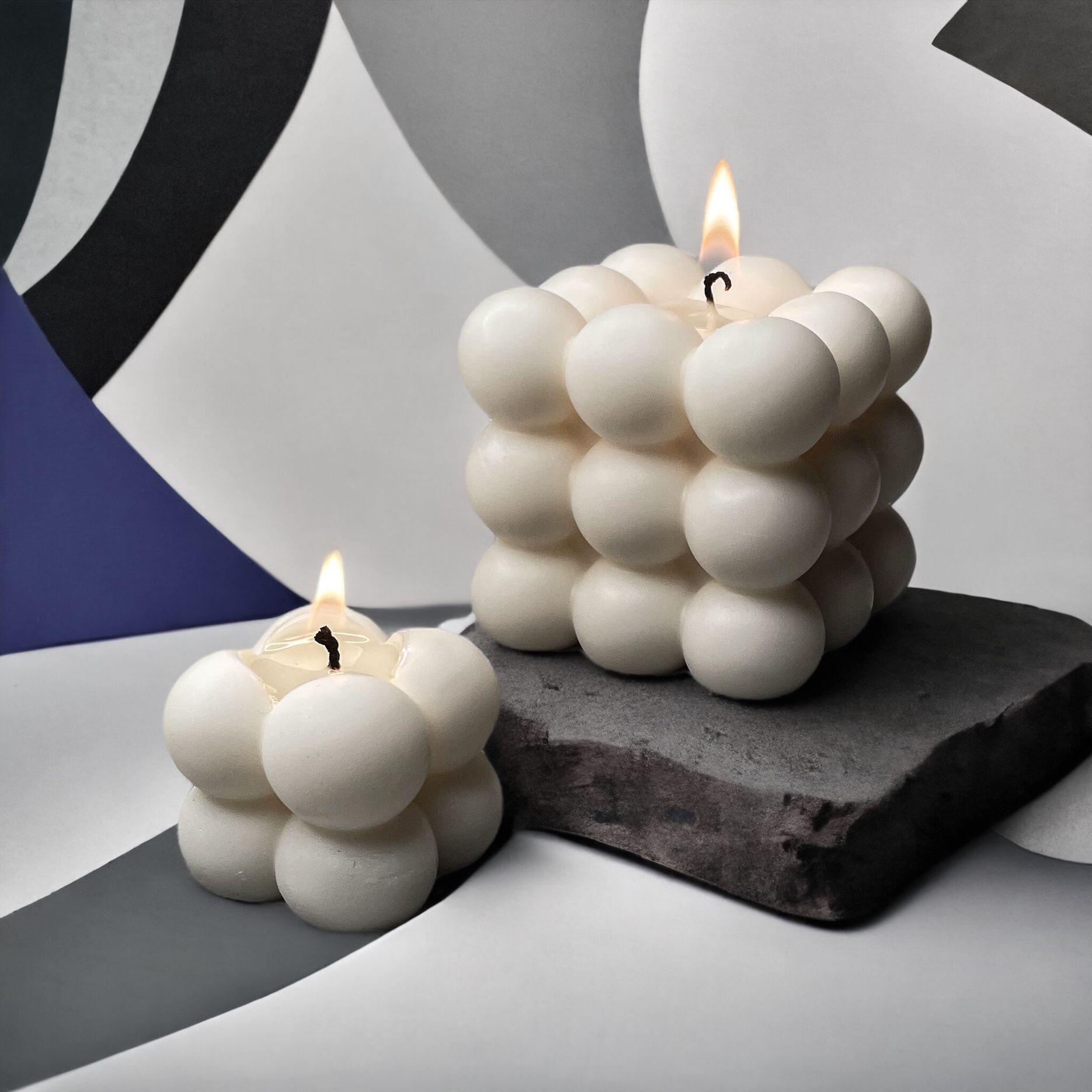 Twee witte bubbelkaarsen staan ​​op een rots