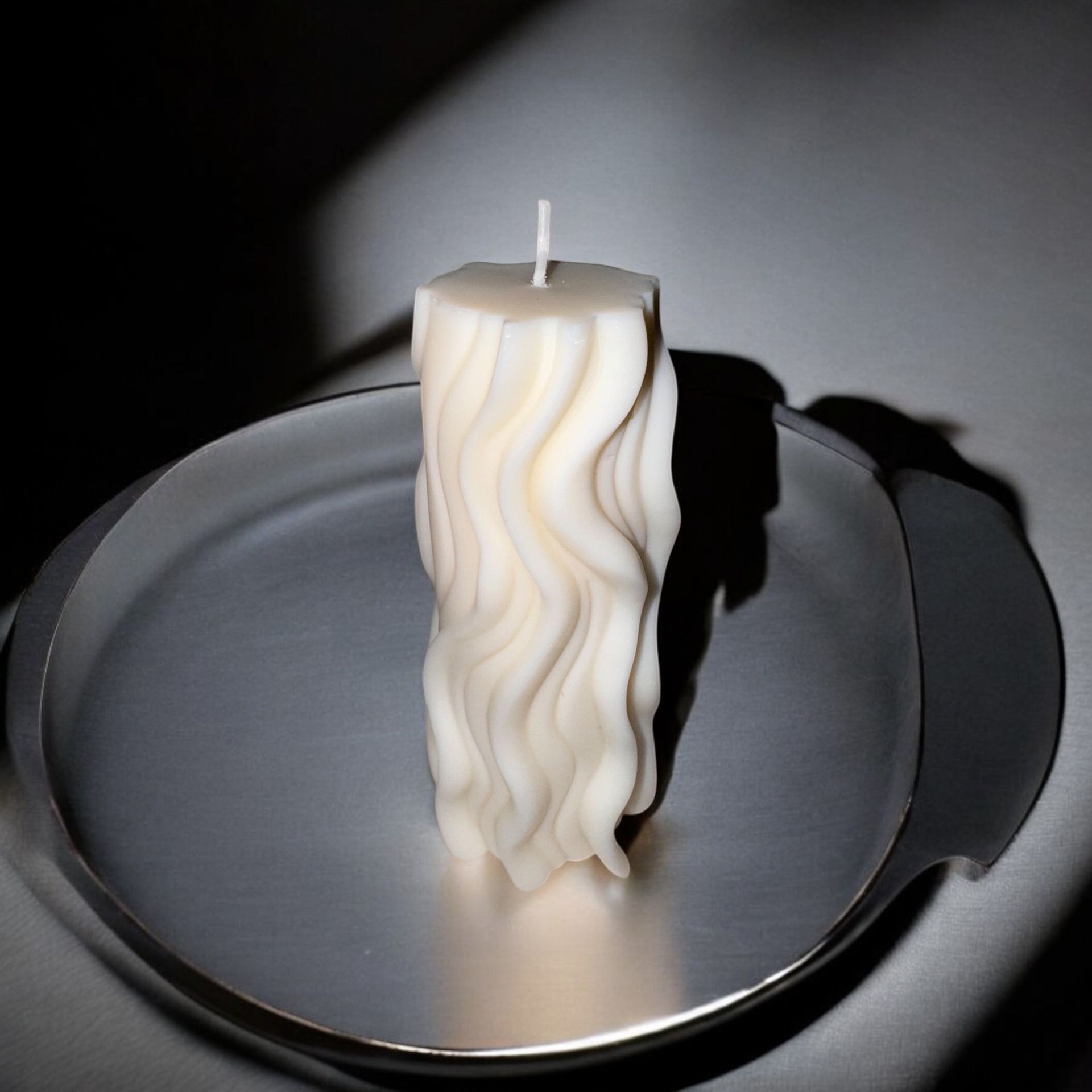 Een witte kaars staat op een zilveren bord