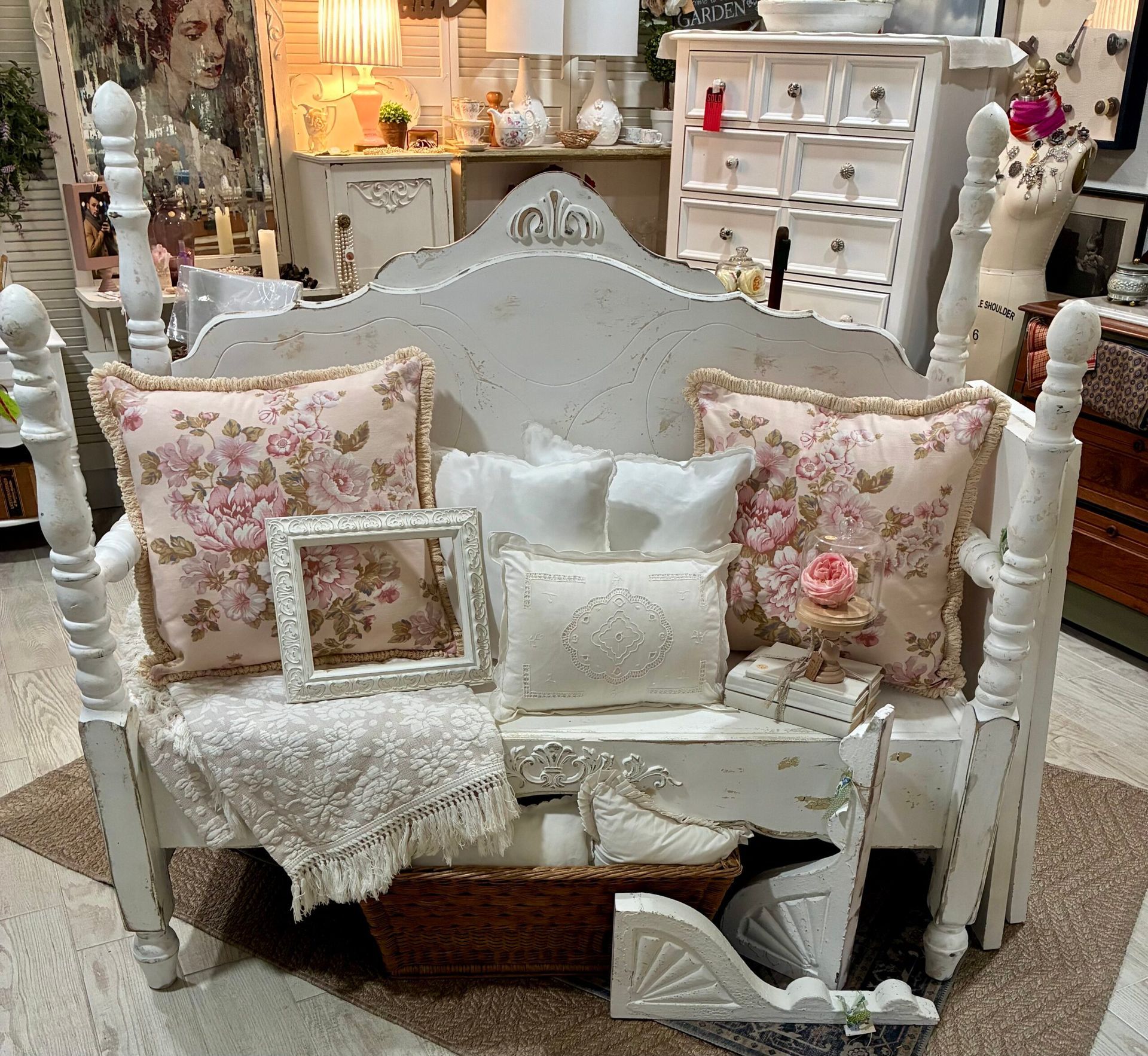 White shabby chic bench with floral pillows, framed picture, and decorative accents.