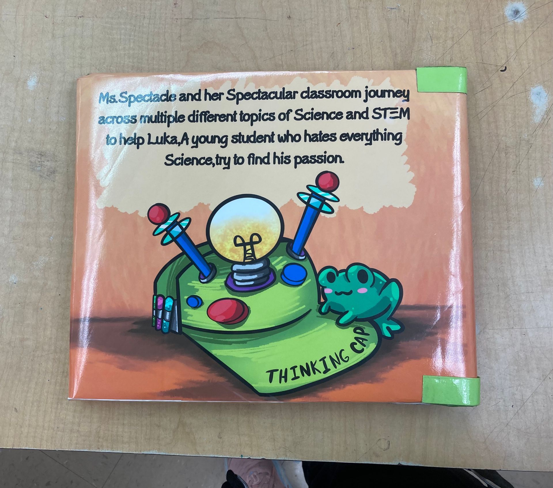 Back cover of a children's book: a cartoon hat with lightbulb, frog, text about science topics.