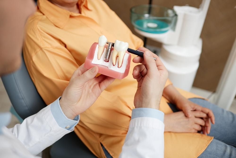 A dentist is showing a model of a dental implant to a patient.