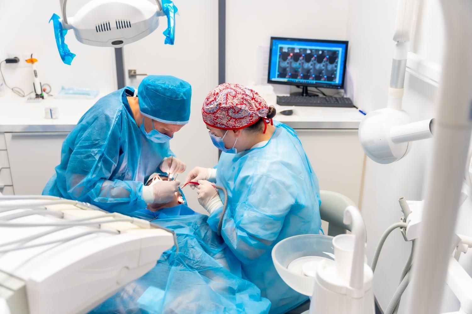 Two dentists are working on a patient in a dental office.