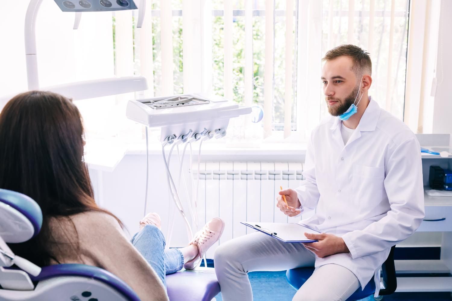 A dentist is talking to a patient in a dental chair.