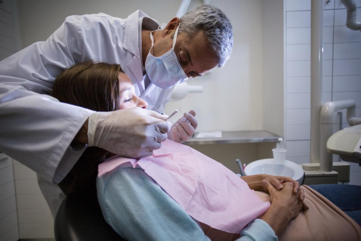 A dentist is examining a patient 's teeth in a dental office.