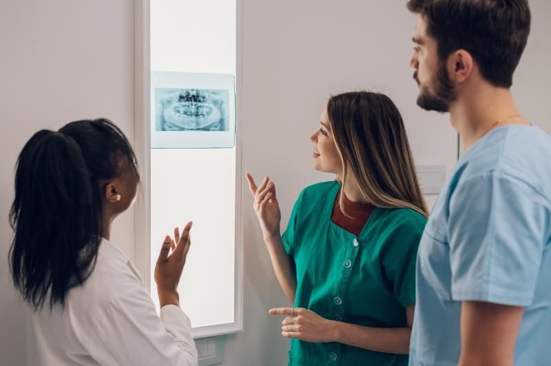 A group of dentists are looking at an x-ray of a patient 's teeth.