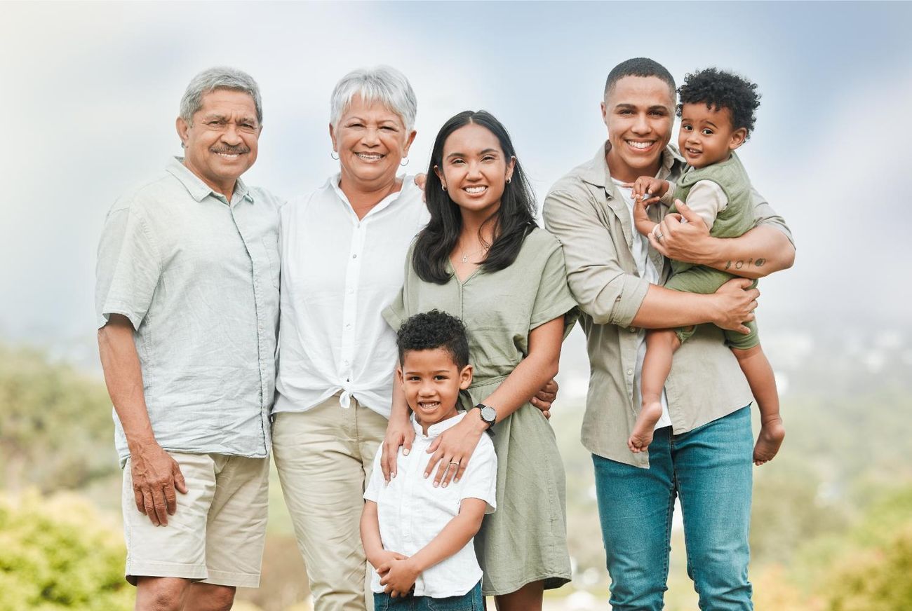 A large family is posing for a picture together in a park.