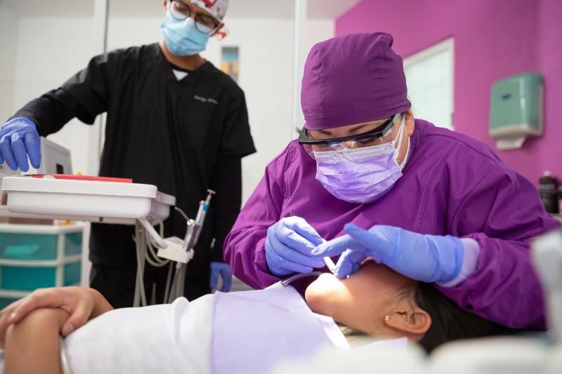 A dentist is examining a child 's teeth in a dental office.