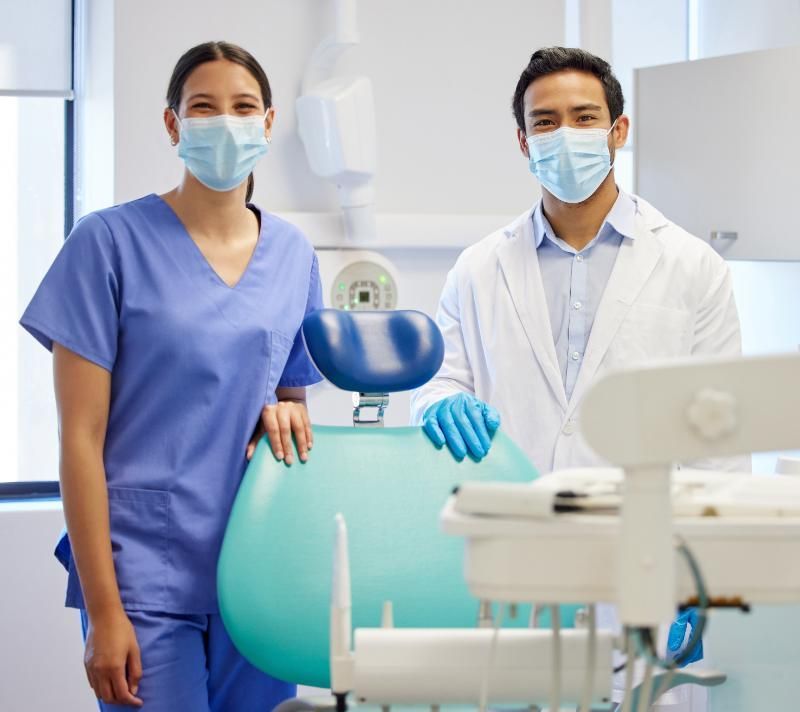 A dentist and a nurse wearing face masks in a dental office