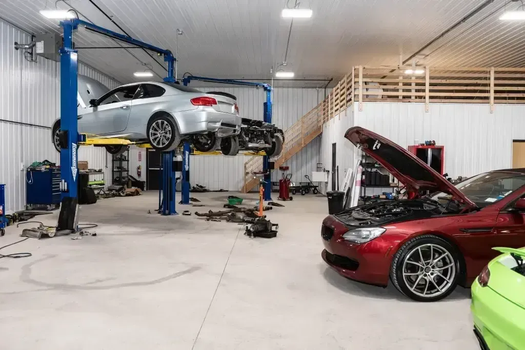 Silver car raised up with red on floor with hood up in garage | Eurocharged