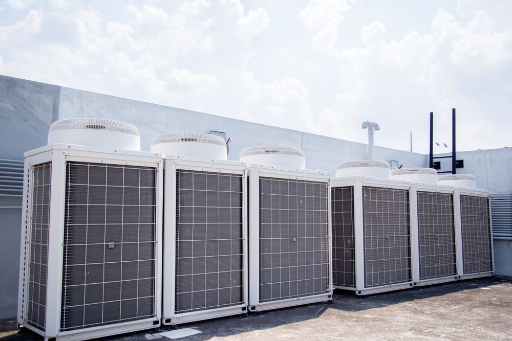 Air conditioning units on a rooftop against a partly cloudy sky.