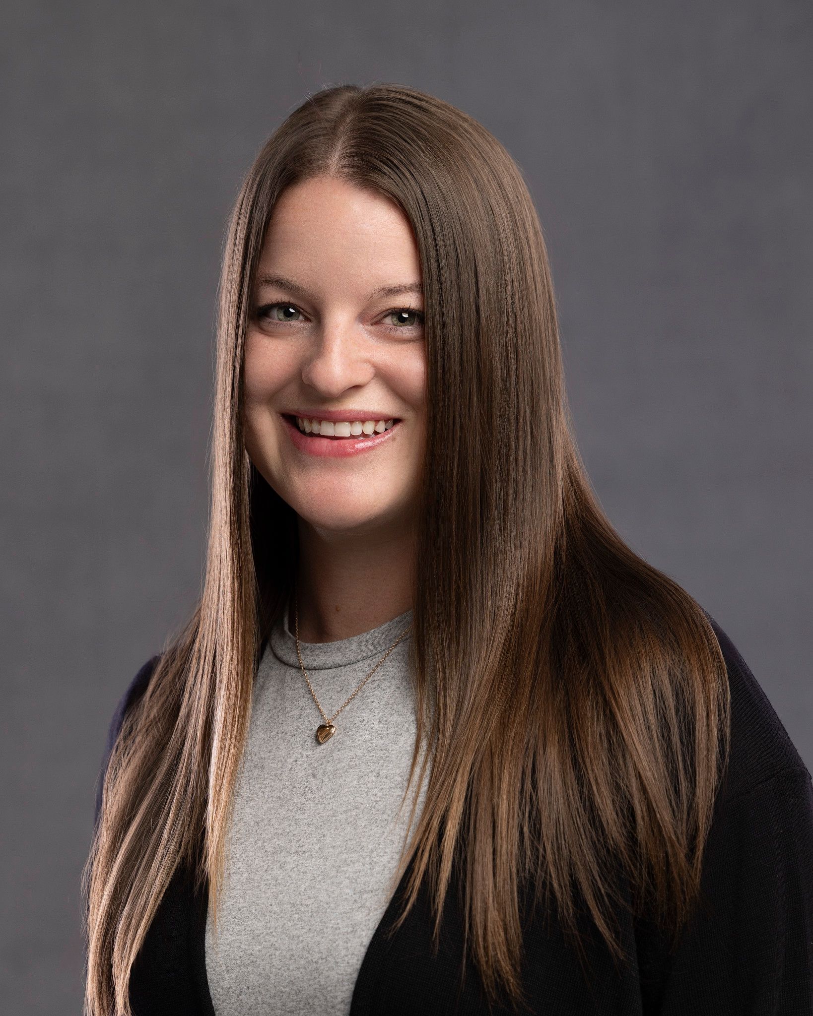 A woman wearing a black jacket and a blue shirt is smiling for the camera.