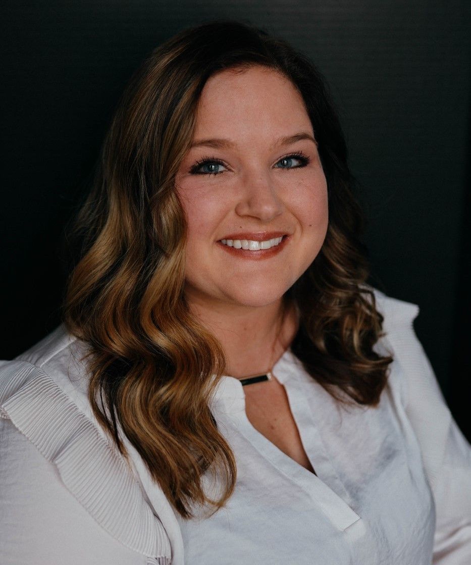 A woman in a white shirt is smiling for the camera.