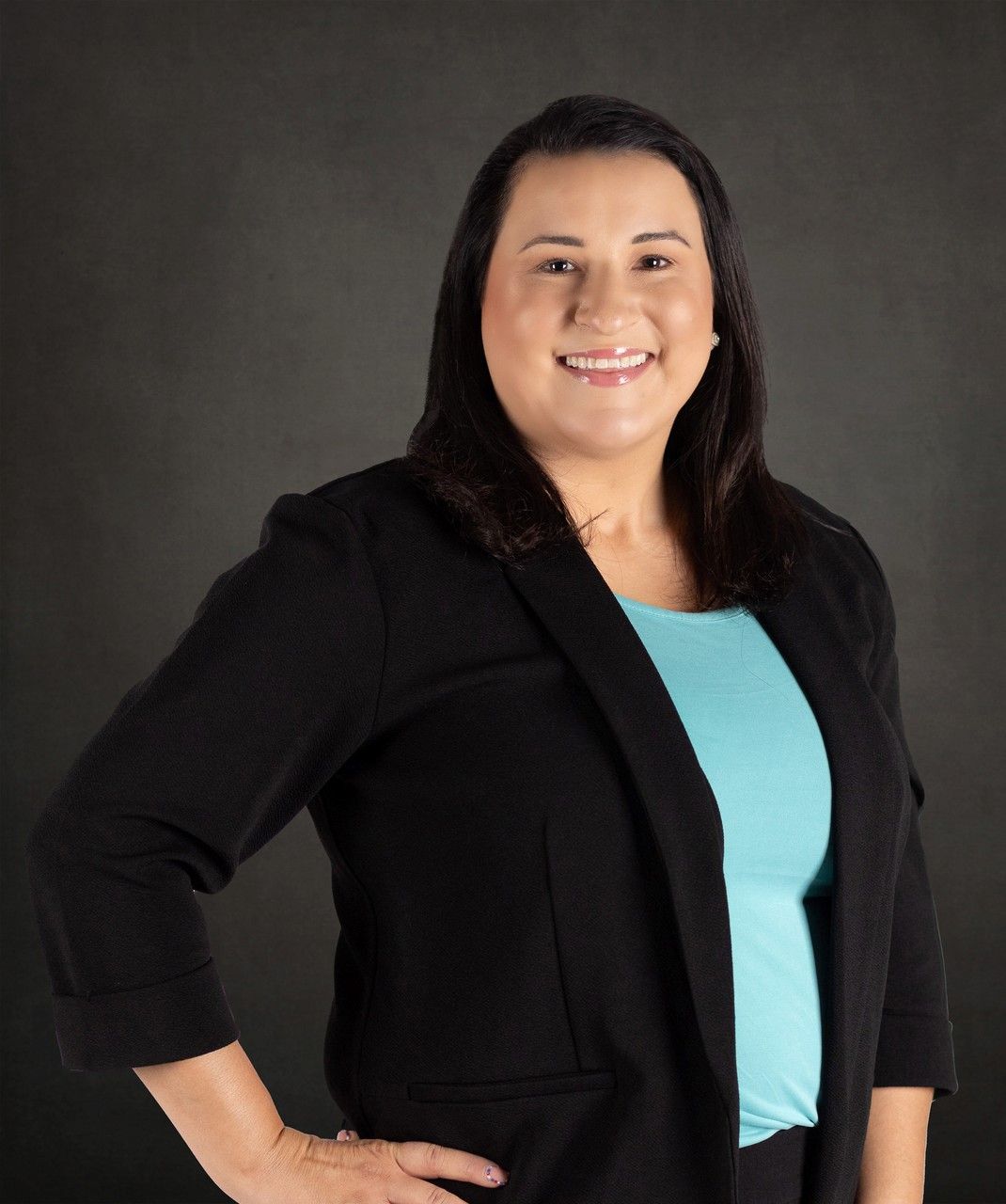 A woman wearing a black jacket and a blue shirt is smiling for the camera.