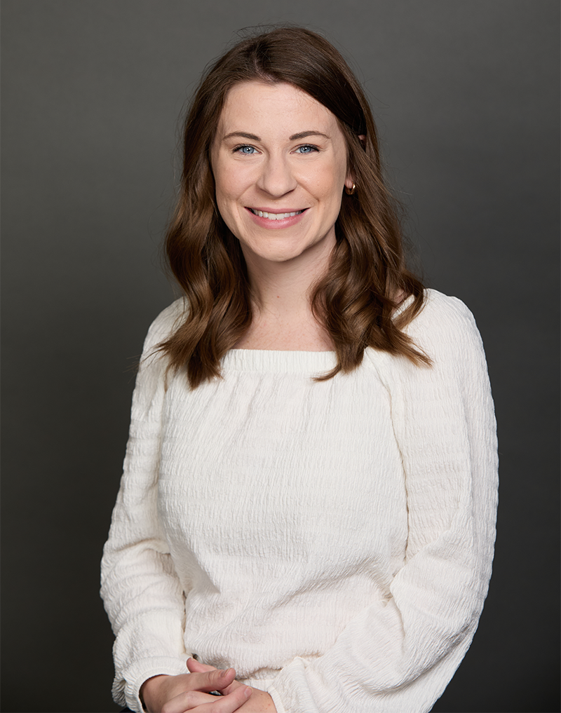 A woman wearing a white sweater and smiling for the camera.