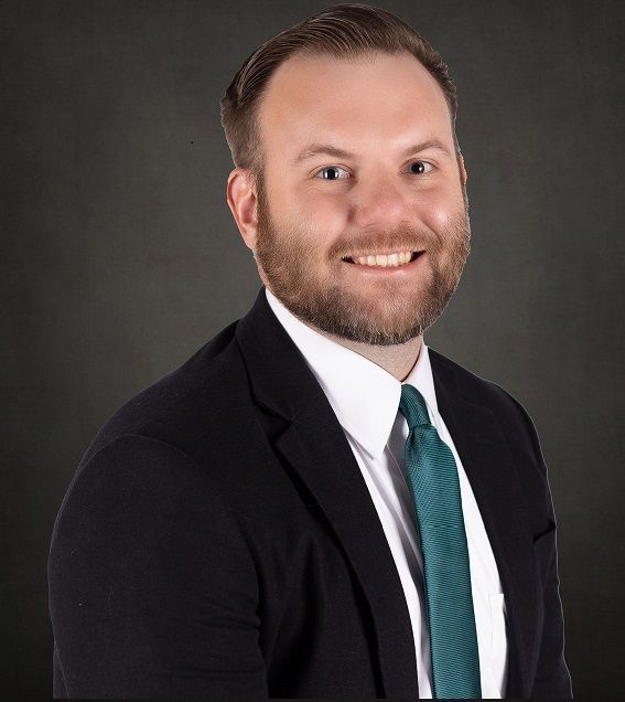 A man in a suit and tie is smiling for the camera.