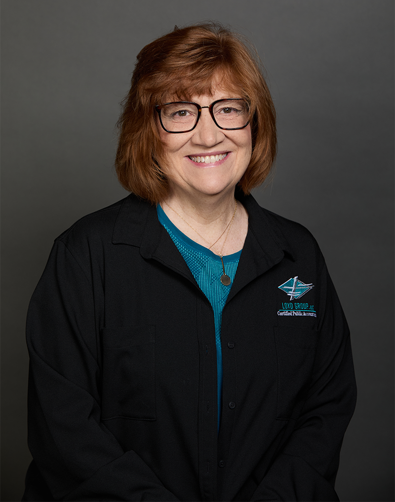 A woman wearing glasses and a black jacket is smiling for the camera.