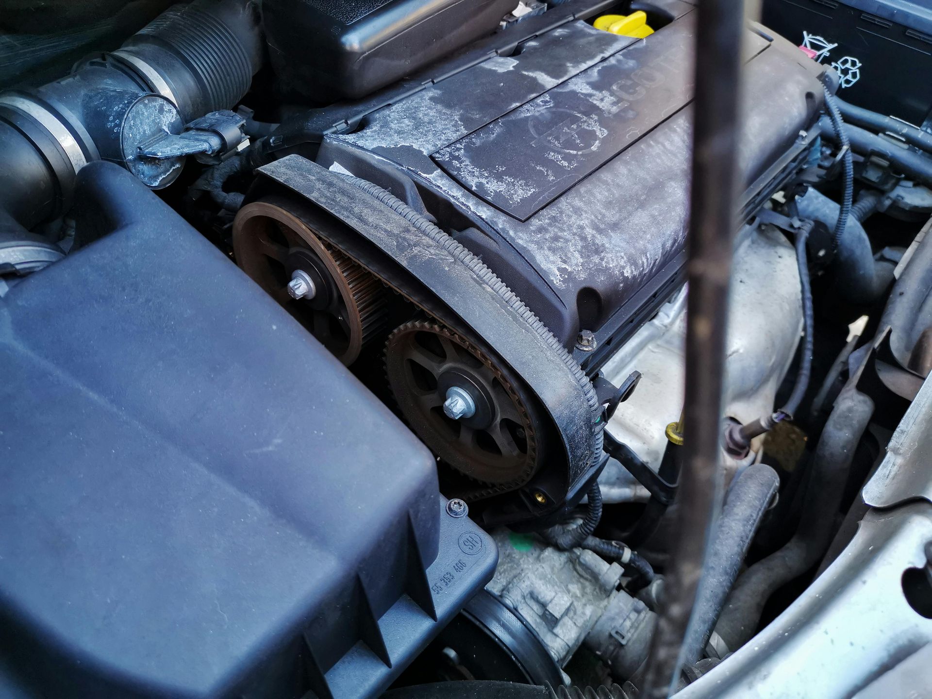 A close up of a car engine with a screwdriver in it