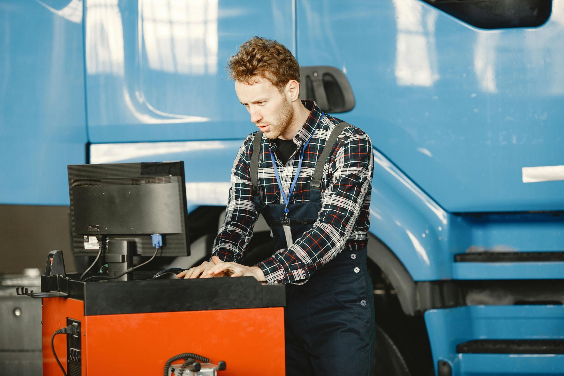 A man is working on a computer in front of a blue truck.