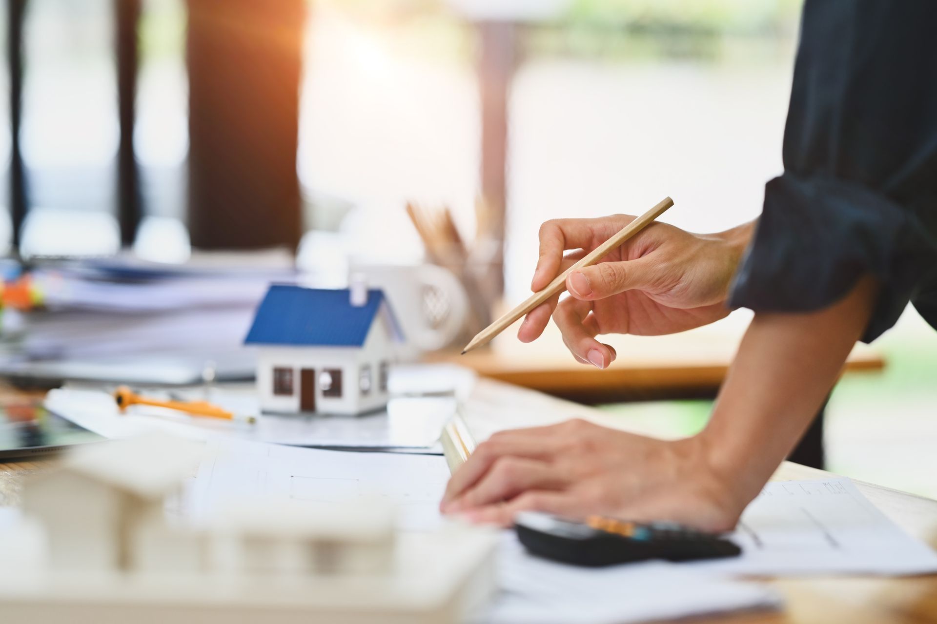 A Person Is Holding a Pencil in Front of a Model House — Rogers, MN — Supplement Negotiators LLC