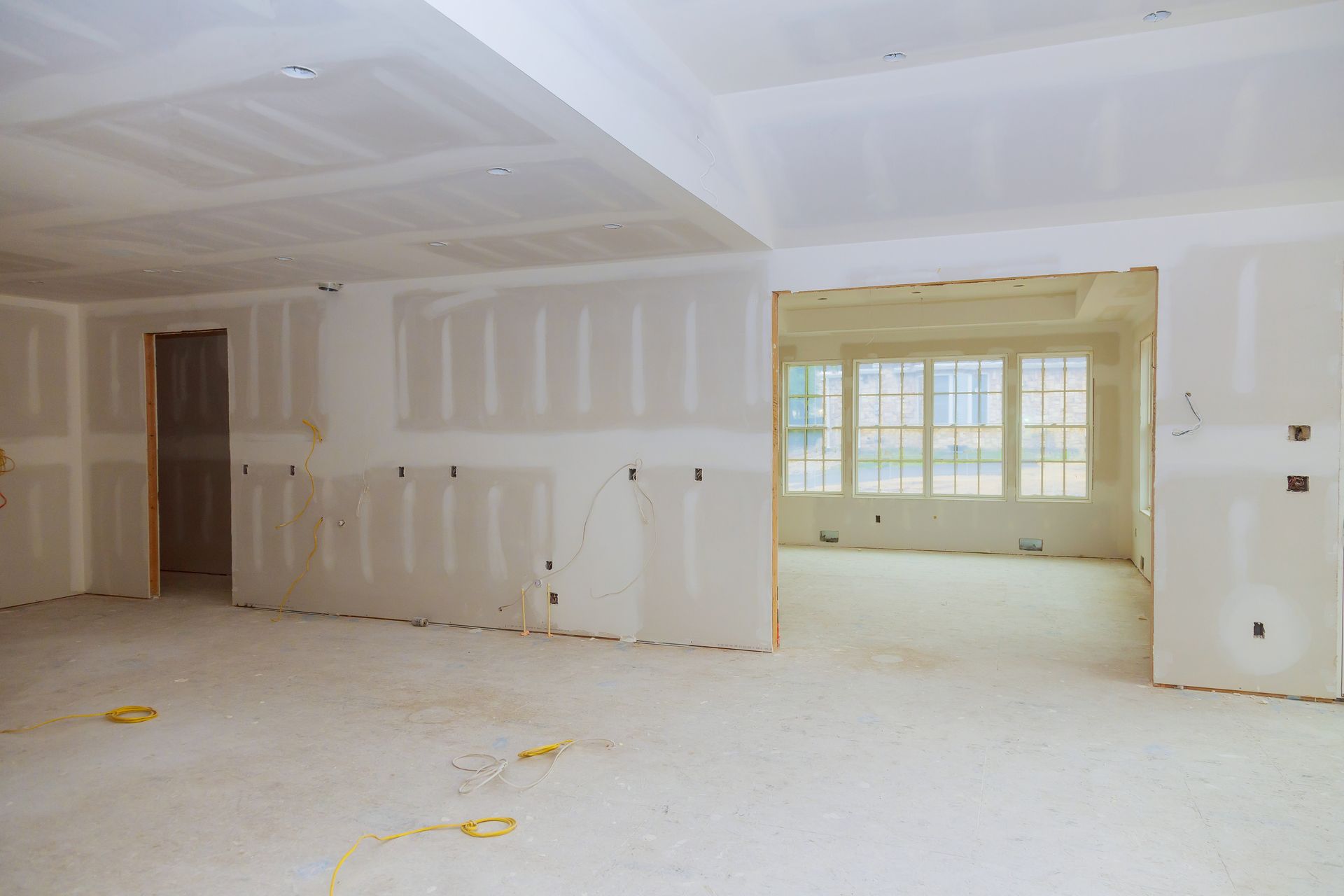 A large empty room with drywall on the walls and a lot of windows.