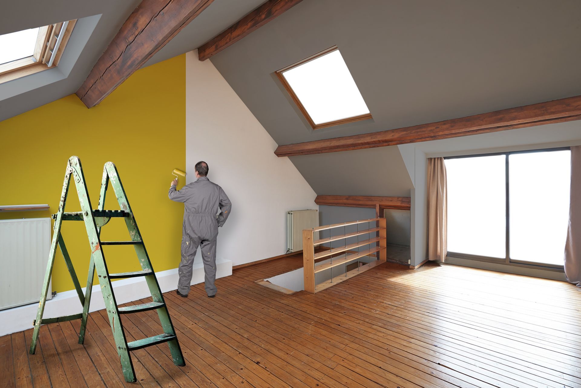 A man is painting a yellow wall in an empty room