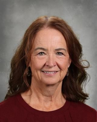 A woman wearing a lanyard that says think about what is smiling for the camera.