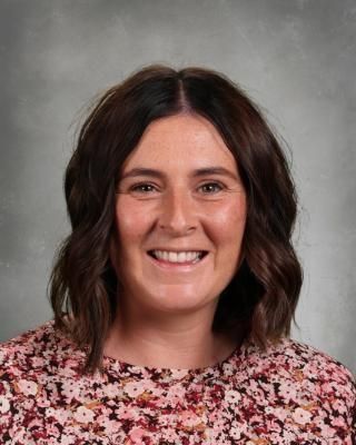 A woman in a pink shirt is smiling for the camera.