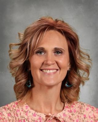 A woman is wearing a sweater and smiling for the camera.