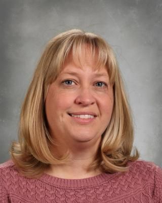 A woman with blonde hair and blue eyes is smiling for a picture.