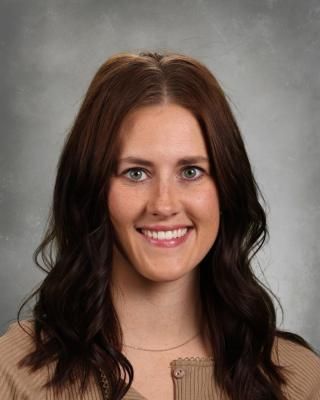 A woman in a red and white checkered shirt is smiling for the camera.