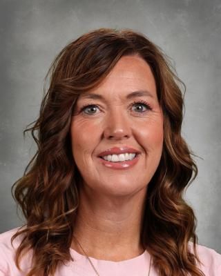 A woman in a white shirt with hearts on it is smiling for the camera.
