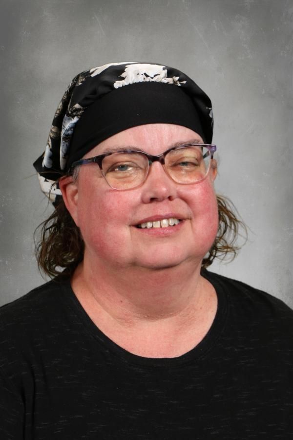 A woman wearing glasses and a bandana is smiling for the camera.