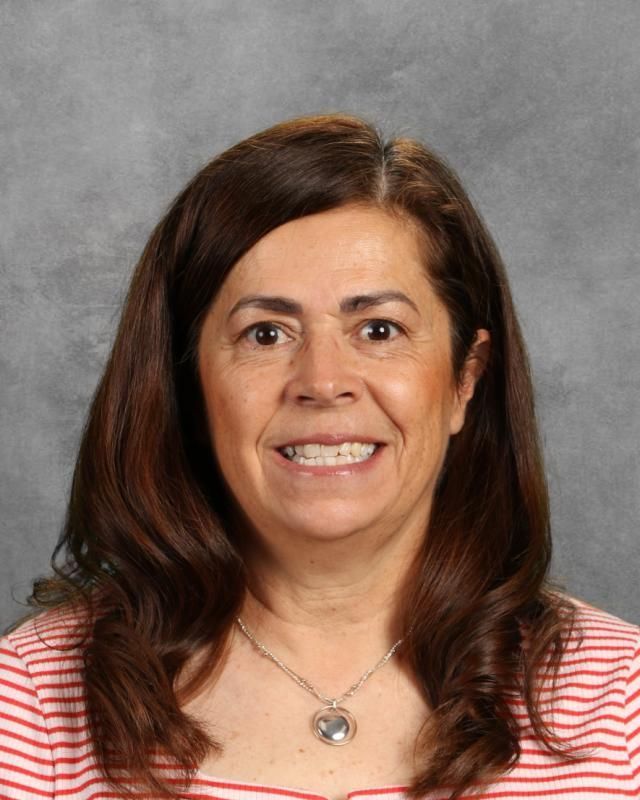 A woman wearing a red and white striped shirt and a necklace is smiling for the camera.