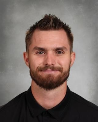 A man with a beard and mustache is wearing a black nike polo shirt.