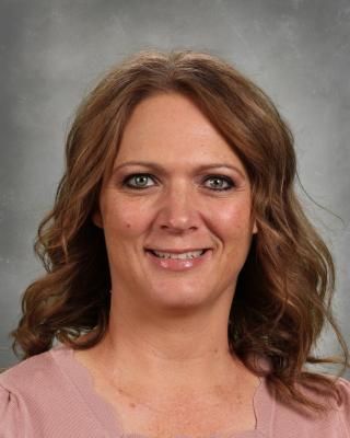A woman with long brown hair is smiling for a picture.